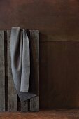 Grey felt blanket hanging on pallet against corten steel wall