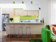 Kitchen with spring green accents and Ghost stools at kitchen counter; green sofa in foreground
