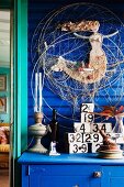 Blue-painted wood cladding and maritime ornaments on chest of drawers; view through turquoise doorframe to one side