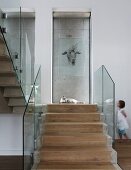 Stone steps with central strip of wooden treads and glass balustrade, drawing of animal on glass pane and little girl in background