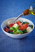 Greek salad being mixed with olive oil