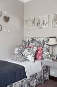 Hearts and framed mirrors above bed with frame upholstered in Toile de Jouy fabric