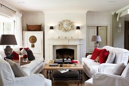 White sofas and coffee table in front of open fireplace in traditional, elegant country house