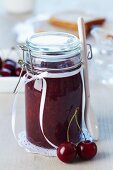 A jar of cherry jam decorated with a bow as a present