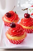 Cupcakes topped with cherry buttercream and cherries