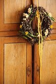 Frühlingskranz aus Birkenzweigen, Palmkätzchen und Frühlingsblumen an Schranktür gehängt