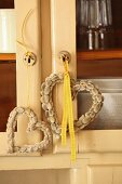 Heart-shaped wreaths of pussy willow hanging from keys of glass-fronted cabinet
