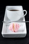 cup of coffee with small pink meringue