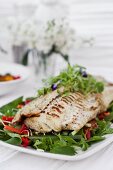 Fried fish fillet on a bed of vegetables and lettuce