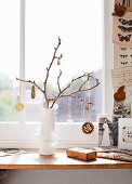 Jewellery hanging on twig in white vase on window sill