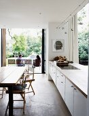 Offene Küche mit weisser Küchenzeile als Raumteiler und Terrassenzugang