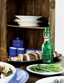 Table set with starters and sliced bread; crockery in open-fronted wooden cabinet in background