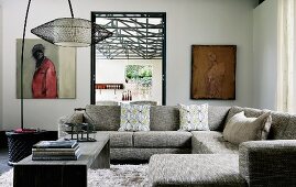 Comfortable, grey sofa combination and minimalist coffee table below jaunty arc lamp with mesh lampshade in corner of modern interior