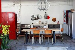 Retro table and chairs in front of kitchen counter and red cupboard to one side in loft-style interior