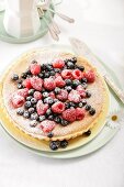 Coconut and lemon tart with fresh berries and icing sugar