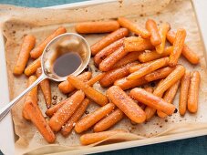 Oven-roasted baby carrots with balsamic vinegar, on the baking tray