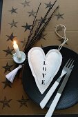 Decorative idea: Christmas tree candle holder clipped to twigs next to place setting with fabric heart and cutlery