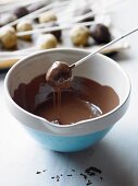 Cake pops being dipped in melted chocolate