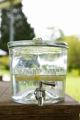 Glass container used as water dispenser on table in garden