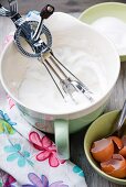 Whisked egg whites in a mixing bowl with a rotary hand whisk