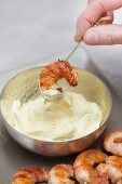 Prawn skewers being dipped in mayonnaise