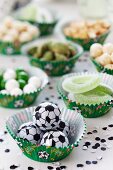 Various snacks arranged in muffin cases with football decorations