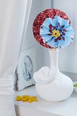 Colourful paper flowers in white china vase
