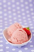 Two scoops of home-made strawberry ice cream with a fresh strawberry