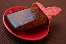 A home-made cola ice lolly on a plate