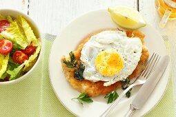 Veal schnitzel with a fried egg, lettuce and beer