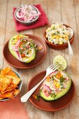 Avocado filled with smoked mackerel and a sweetcorn salad, topped with red onions and served with tortilla chips