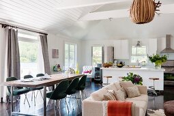 Long dining table and classic chairs (Executive by Saarinen), seating area with sofa and open-plan kitchen with breakfast bar