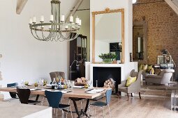 Set dining table and chandelier in modern, loft-style renovated barn with exposed stone wall in background