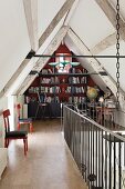 Kleine Bibliothek im Dachspitz einer umgebauten Scheune mit Brüstungsgeländer und gepolsterten Holzstühlen