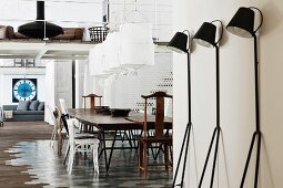 Retro, black metal standard lamps against wall in front of dining area in loft apartment