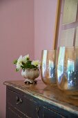 Glass vases and bowl of flowers on vintage chest of drawers