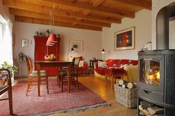 Living room in shades of red with sofa, dining table & log burner in village house (Eggelingen, Ostfriesland, Germany)