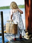 Mädchen mit Korbtasche auf einem Bootssteg