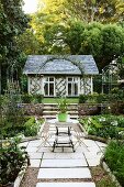 Gartenanlage mit symmetrisch angelegten Beeten und mit Blickauf das Gartenhäuschen mit Spalier