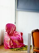 Chair wrapped in pink fabric in corner of room