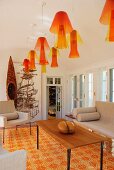 Interior with row of yellow and orange plexiglass pendant lamps and floor tiles in the same colours