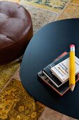 View down onto black metal table and brown leather pouffe on patterned rug