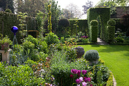 Blühender Garten mit kunstvoll geschnittenen Hecken im englischen Stil