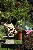 Sunny seating area in garden with metal furniture and chequered floor of stone slabs and lawn squares; teapot and teacups on table