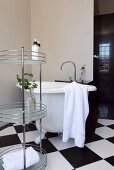 Free-standing, metal shelving unit and vintage bathtub on chequered floor in corner of bathroom