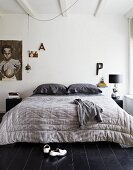 Large quilt on double bed in bedroom with black wooden floor