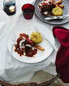 Dining table with plates of lamb shank and potato rosti