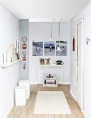 DIY renovations - grey-painted hallway, set of white stools to one side below floating shelf and delicate console table in background below gallery of photos