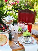 Table in garden set with berries, lettuce seedlings and teapot