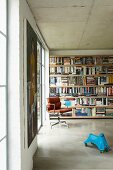 Retro Bürostuhl und Kinderspielzeug vor Bücherwand in puristischem Raum mit Sichtbetondecke